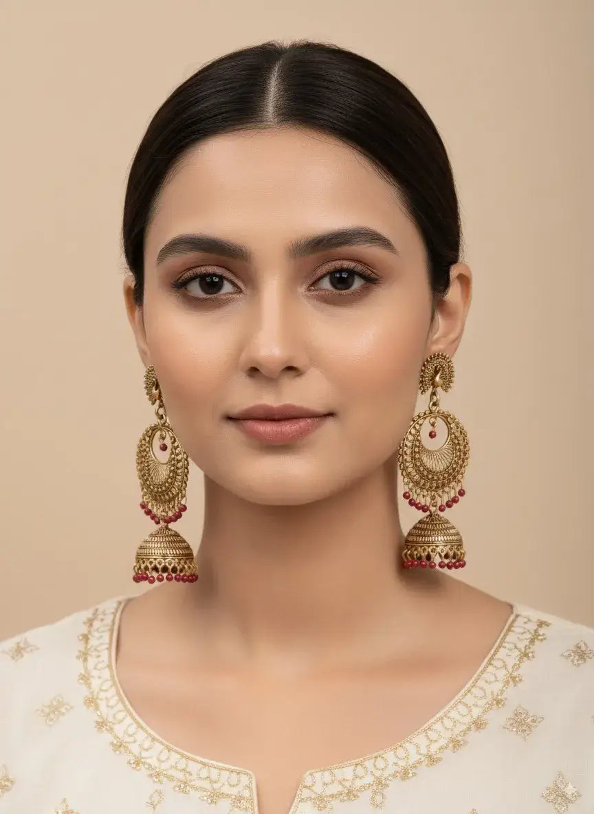 gold plated jhumka earrings with red beads | ethnic indian jewelry for women, worn by a model, showcasing traditional style.