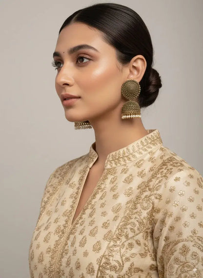 Antique Gold Oversized Dome Stud Jhumka Earrings with Pearl Drops worn by a woman in a traditional outfit.