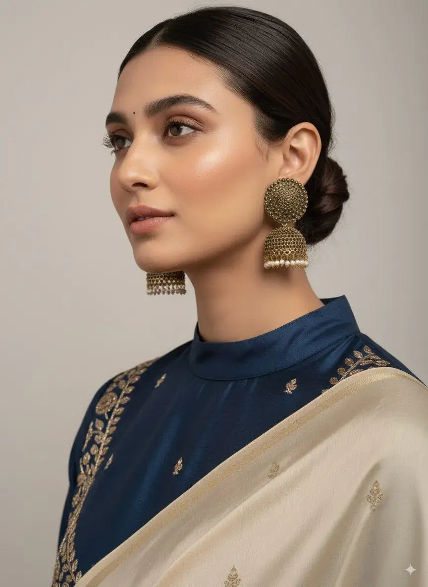 antique gold oversized dome stud jhumka earrings with pearl drops worn by a model in traditional attire.