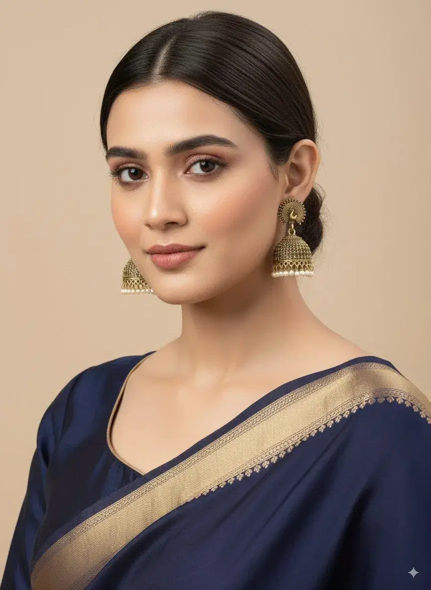 antique gold peacock jhumka earrings with pearl drops – traditional jewellery worn by a model.