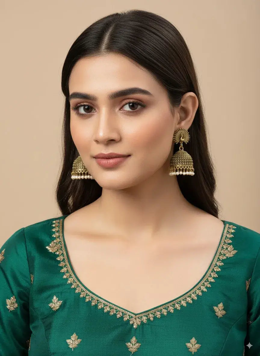 antique gold peacock jhumka earrings with pearl drops – traditional jewellery showcased on model.