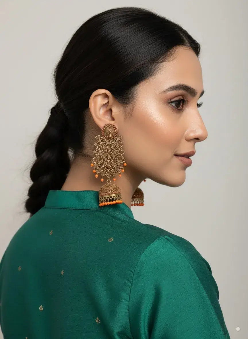 model wearing gold plated long jhumka earrings with orange beads – ethnic & bridal jewellery styled with green outfit.