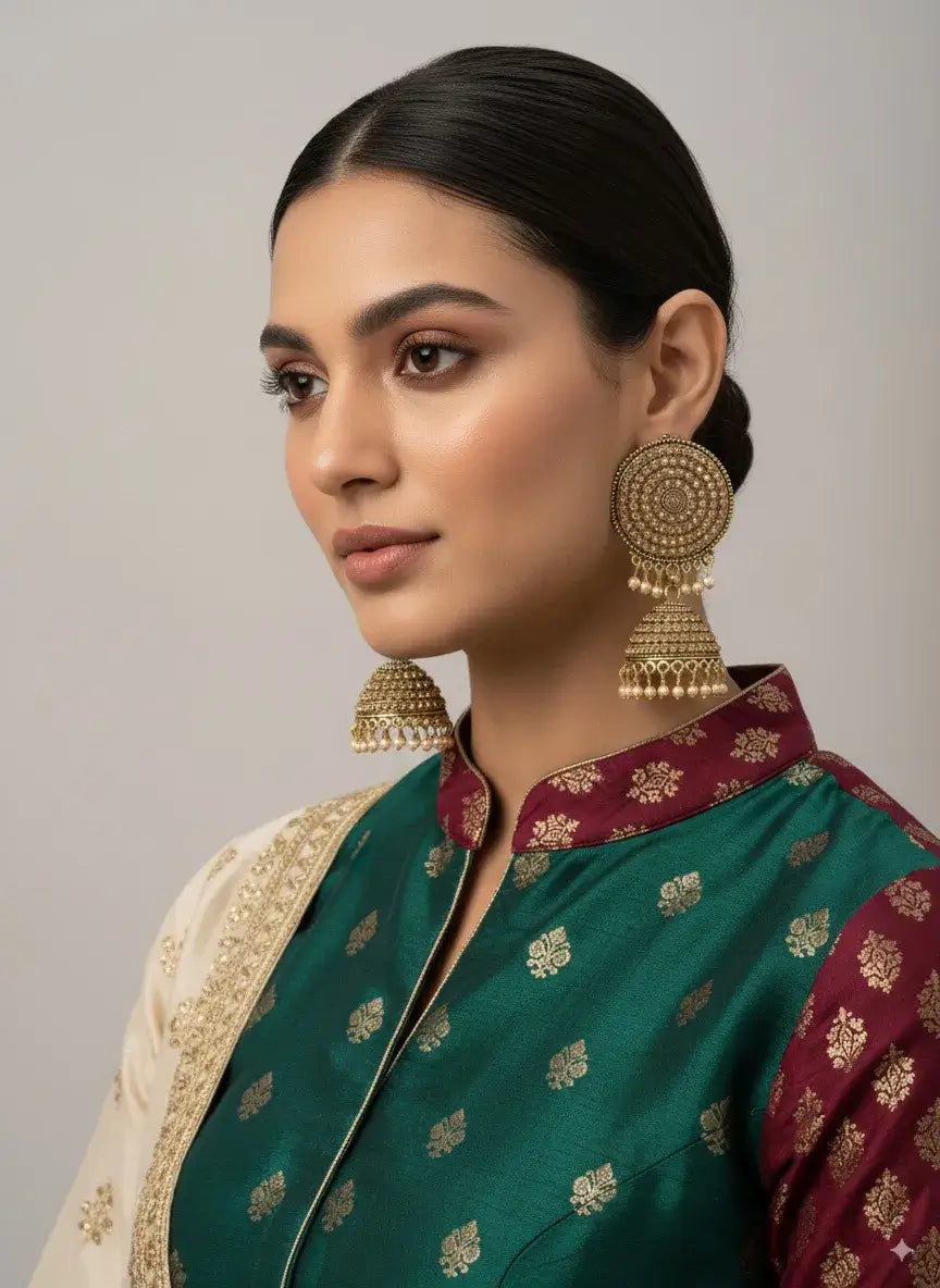 gold plated round jhumka earrings for women | traditional bridal party wear worn by model in elegant attire.