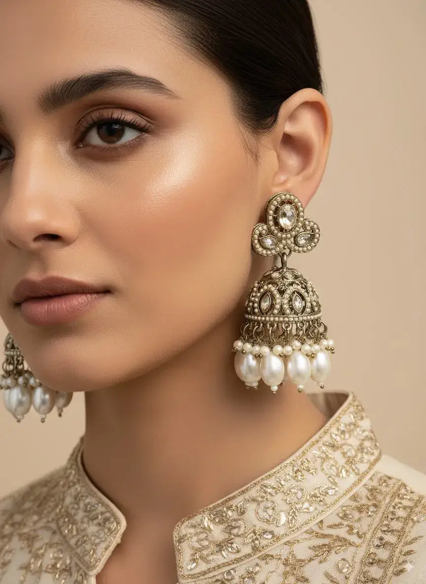 Antique Gold Plated Jhumka Earrings with Pearls worn by a model showcasing traditional motifs and pearl drops.
